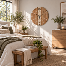 Load image into Gallery viewer, Large rustic wooden wall clock with carved floral detail in a bright, modern bedroom.
