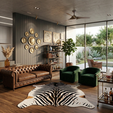 Load image into Gallery viewer, Large faux zebra print rug in stylish living room with brown leather sofa and green velvet chairs
